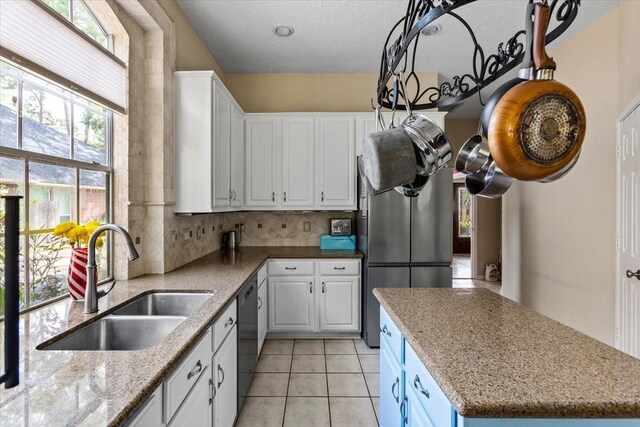 kitchen featuring backsplash, dishwasher, light stone counters, sink, and white cabinets