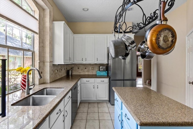 kitchen with light stone counters, black dishwasher, white cabinetry, a sink, and a kitchen island