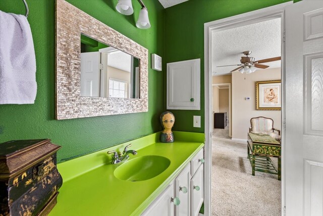 bathroom with vanity, ceiling fan, and a textured ceiling