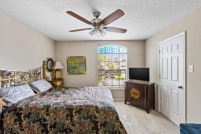 bedroom with a textured ceiling, ceiling fan, and light carpet