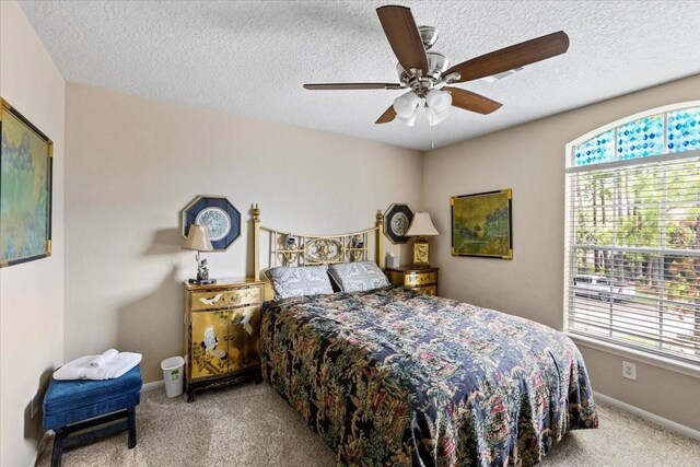 bedroom featuring light colored carpet, ceiling fan, and a textured ceiling