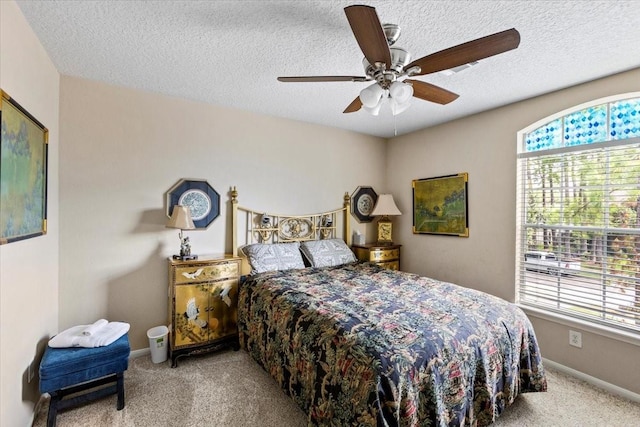 bedroom with a ceiling fan, baseboards, a textured ceiling, and light colored carpet