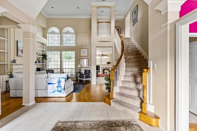 tiled foyer with stairs, a high ceiling, and crown molding