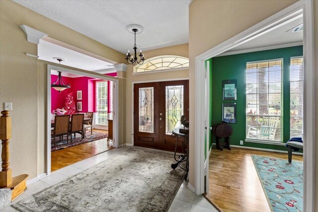 foyer featuring plenty of natural light, french doors, a chandelier, and light hardwood / wood-style floors