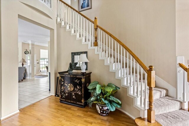 staircase with ornamental molding and wood-type flooring