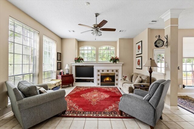 living room featuring ceiling fan, light tile patterned floors, and a textured ceiling