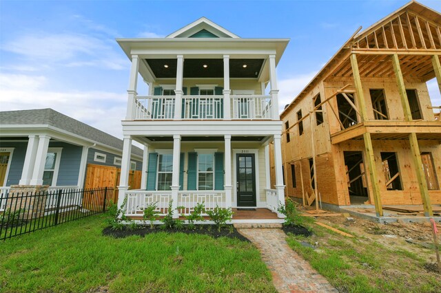 view of front of home with a front yard, a balcony, and a porch