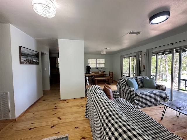 living room featuring a healthy amount of sunlight, an inviting chandelier, and light wood-type flooring