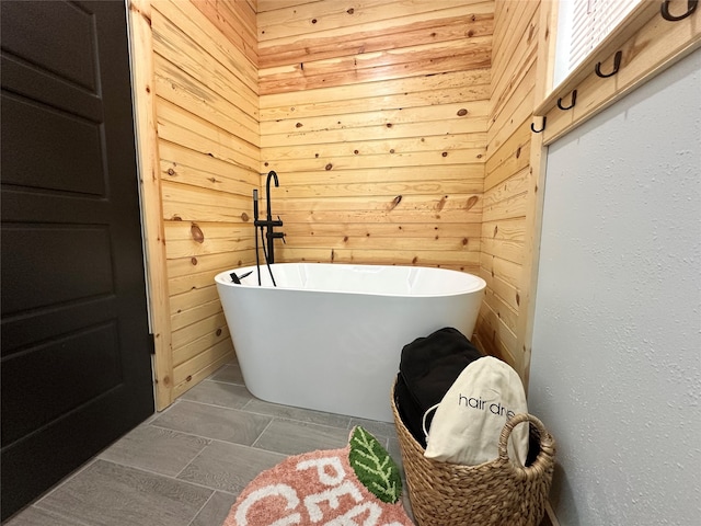 bathroom with wood walls, a bath, and tile patterned floors