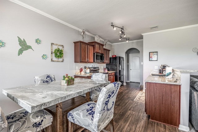 dining area featuring track lighting, sink, crown molding, dark hardwood / wood-style floors, and a textured ceiling