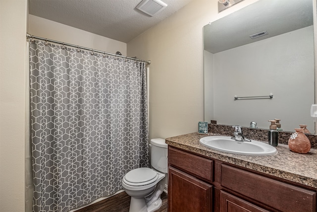 bathroom with vanity, a textured ceiling, and toilet