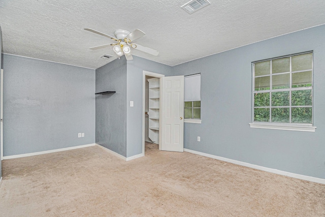 unfurnished bedroom featuring light carpet, ceiling fan, and a textured ceiling