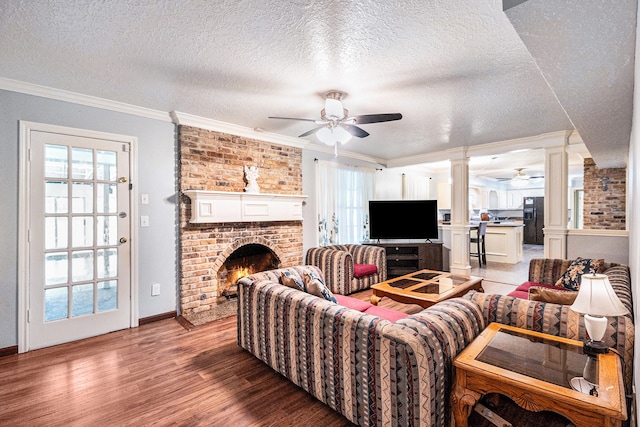 living room featuring a textured ceiling, a brick fireplace, wood-type flooring, and ceiling fan