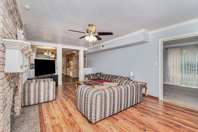 living room featuring light wood-type flooring, ceiling fan with notable chandelier, ornamental molding, and a textured ceiling