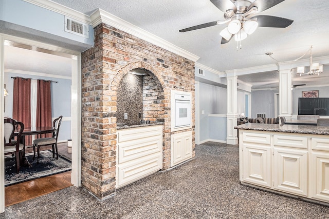 kitchen with a textured ceiling, dark carpet, ornamental molding, and ceiling fan