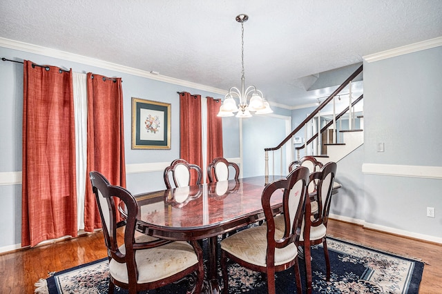 dining space with hardwood / wood-style flooring, a notable chandelier, crown molding, and a textured ceiling