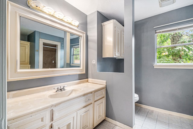 bathroom featuring vanity, tile patterned floors, toilet, and a healthy amount of sunlight