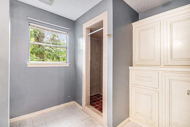 bathroom with tiled shower and tile patterned floors