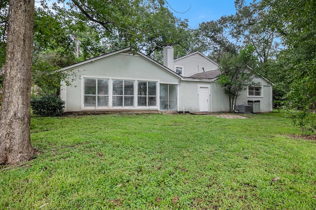 back of property with central AC unit and a lawn