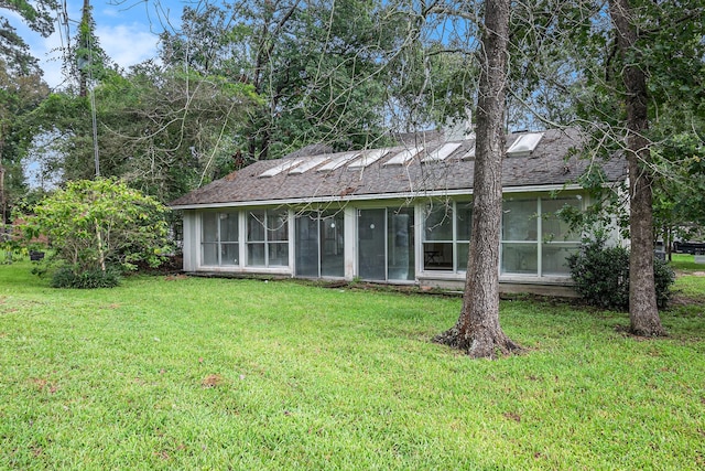 back of property with a sunroom and a yard