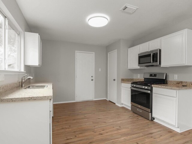 kitchen with a wealth of natural light, light hardwood / wood-style flooring, stainless steel appliances, and sink