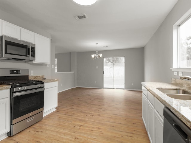 kitchen with light wood-type flooring, an inviting chandelier, sink, appliances with stainless steel finishes, and white cabinets