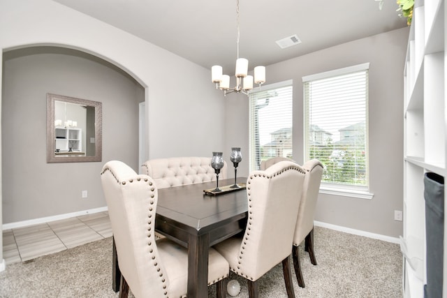 dining area with light tile patterned flooring and an inviting chandelier