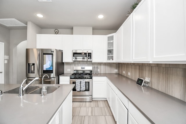 kitchen with sink, stainless steel appliances, backsplash, and white cabinets