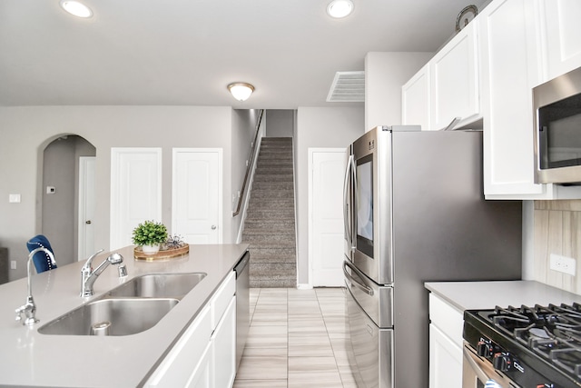 kitchen with light tile patterned flooring, sink, stainless steel appliances, and white cabinets