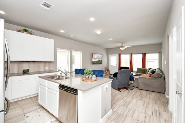 kitchen with appliances with stainless steel finishes, a center island with sink, light tile patterned floors, white cabinetry, and ceiling fan