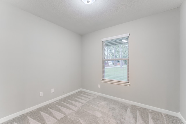 carpeted empty room featuring a textured ceiling