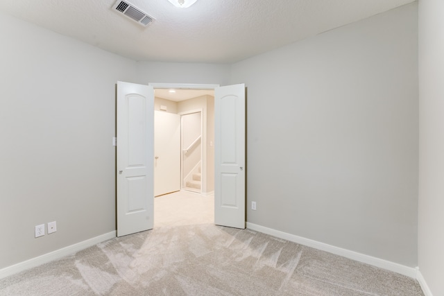 carpeted empty room featuring a textured ceiling