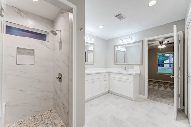 bathroom with a tile shower, double vanity, ceiling fan, and tile patterned floors