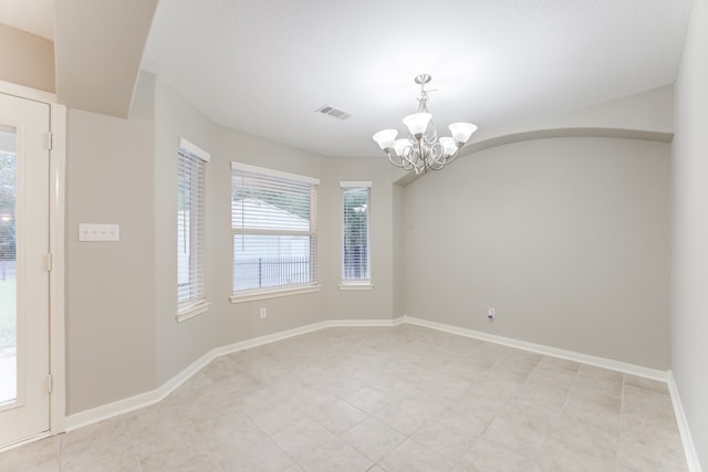 tiled empty room featuring a chandelier