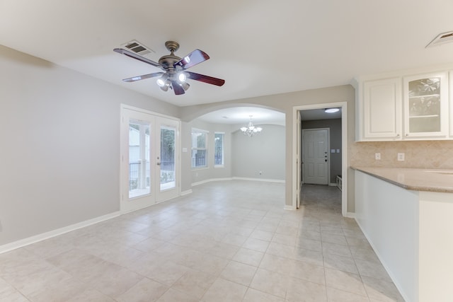 interior space with light tile patterned flooring and ceiling fan with notable chandelier