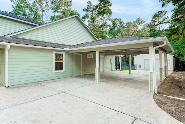 back of house featuring a garage, an outbuilding, and a carport