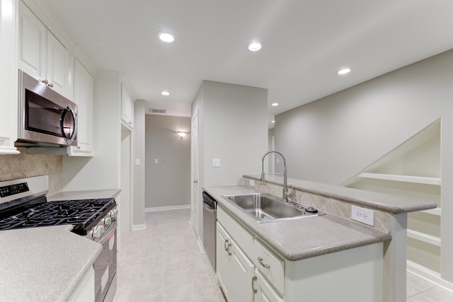 kitchen with white cabinets, decorative backsplash, sink, appliances with stainless steel finishes, and light tile patterned floors