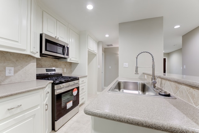 kitchen with appliances with stainless steel finishes, sink, backsplash, light tile patterned floors, and white cabinetry