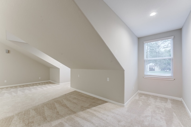 bonus room with lofted ceiling and light colored carpet