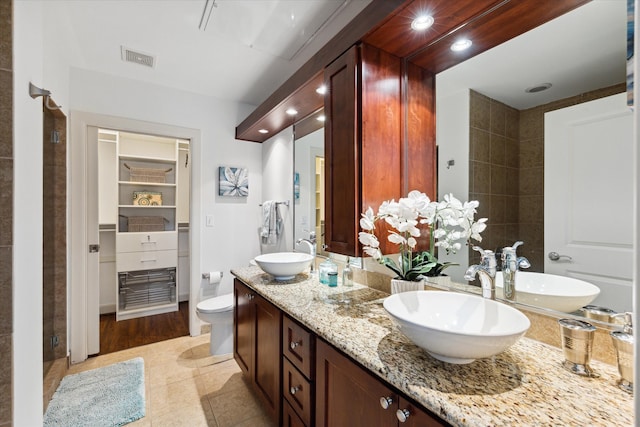 bathroom featuring dual vanity, toilet, and tile patterned floors