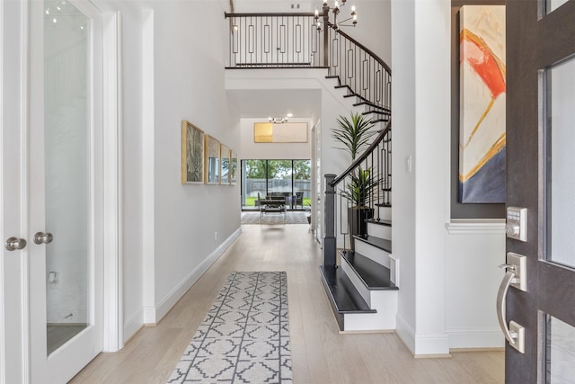 foyer entrance with an inviting chandelier, light hardwood / wood-style floors, and a high ceiling