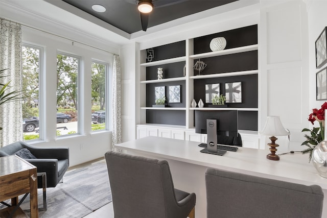 office space featuring a healthy amount of sunlight, built in shelves, built in desk, and ceiling fan