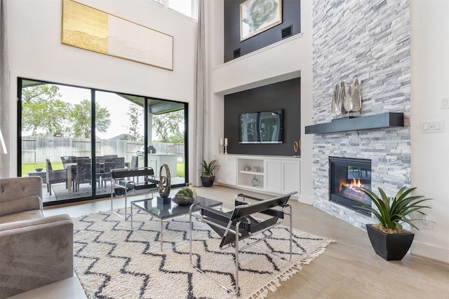 living room with plenty of natural light, a fireplace, hardwood / wood-style flooring, and a towering ceiling