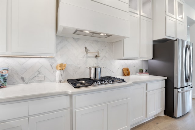 kitchen with light hardwood / wood-style floors, white cabinetry, decorative backsplash, and custom range hood