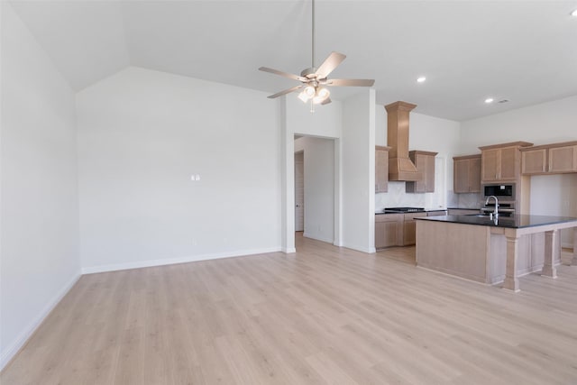 kitchen with sink, premium range hood, an island with sink, built in microwave, and stainless steel gas stovetop