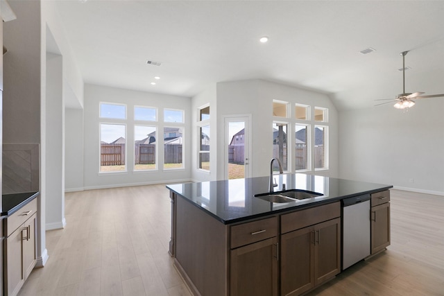 kitchen featuring light wood-type flooring, stainless steel dishwasher, sink, and a wealth of natural light