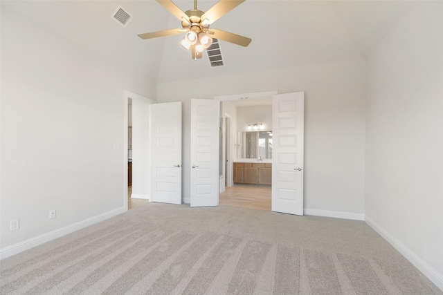 unfurnished bedroom featuring lofted ceiling, sink, ceiling fan, connected bathroom, and light colored carpet