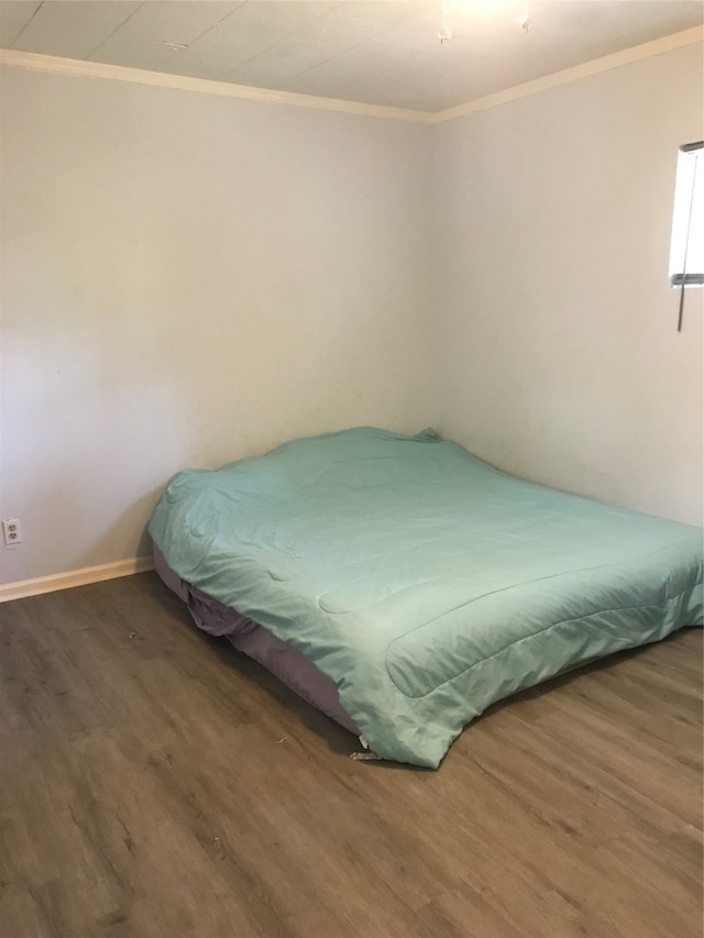 bedroom with ornamental molding and dark wood-type flooring