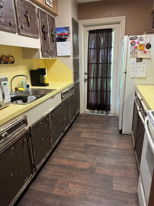 kitchen featuring sink, white appliances, dark hardwood / wood-style floors, and dark brown cabinetry