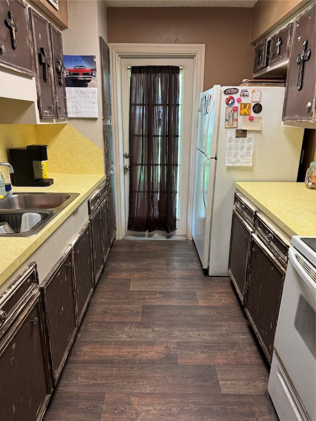 kitchen with sink, white appliances, dark brown cabinetry, and dark hardwood / wood-style floors